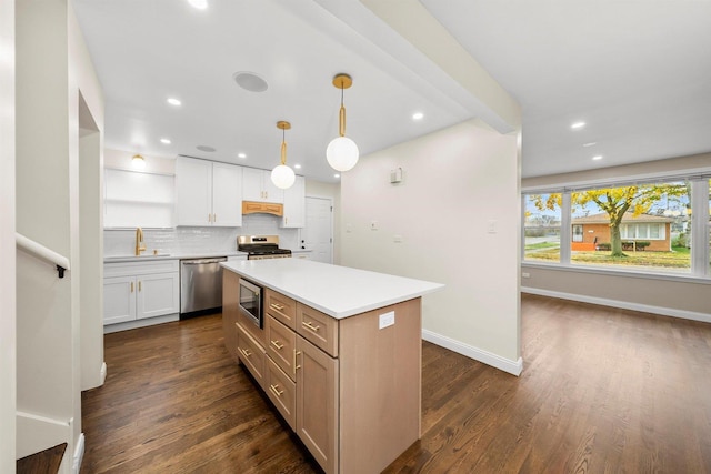 kitchen featuring a center island, sink, decorative light fixtures, white cabinetry, and stainless steel appliances