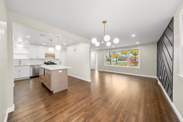 kitchen featuring pendant lighting, backsplash, white cabinetry, and stainless steel appliances