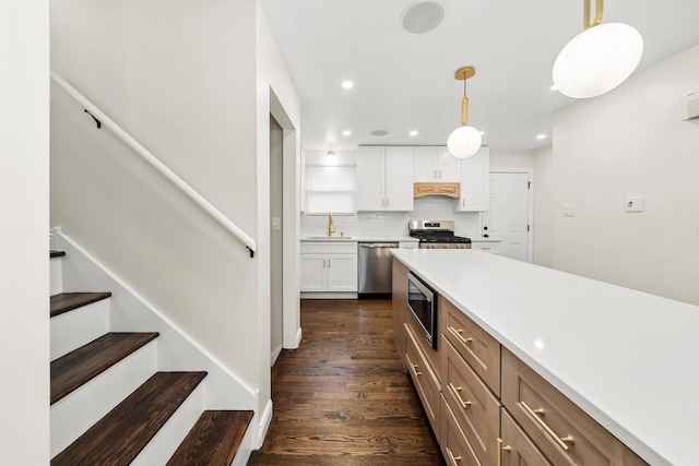 kitchen featuring pendant lighting, backsplash, premium range hood, white cabinetry, and stainless steel appliances