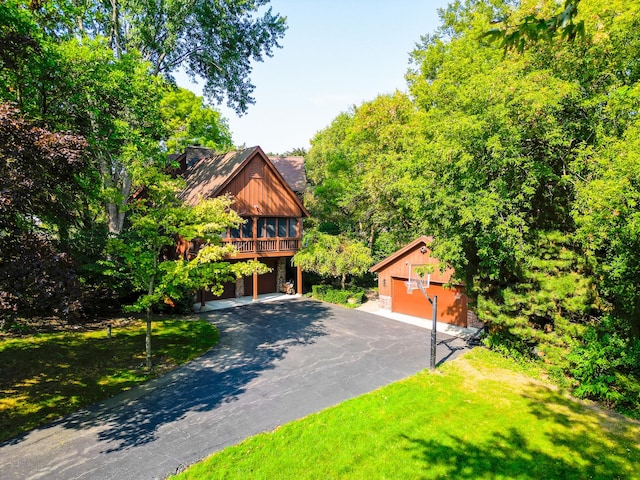 view of front of house with a garage, aphalt driveway, a front yard, and an outdoor structure