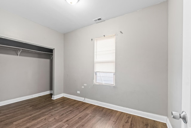 unfurnished bedroom featuring dark hardwood / wood-style flooring and a closet