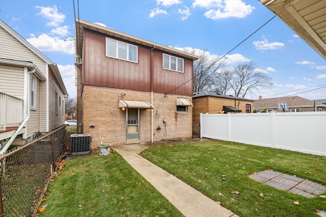 rear view of property with central air condition unit and a yard