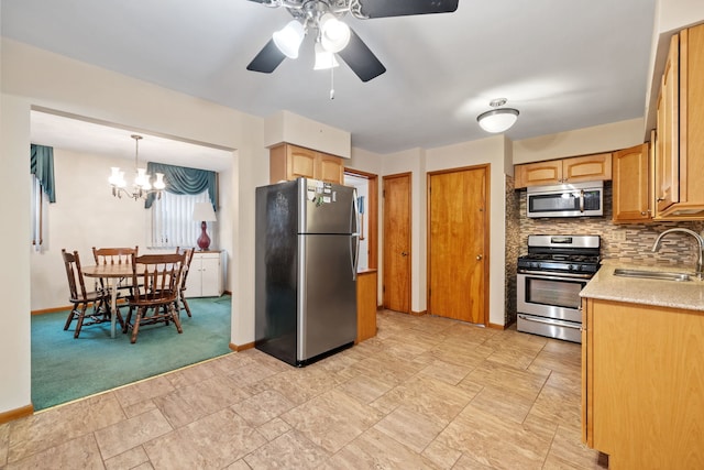 kitchen with sink, hanging light fixtures, stainless steel appliances, tasteful backsplash, and ceiling fan with notable chandelier