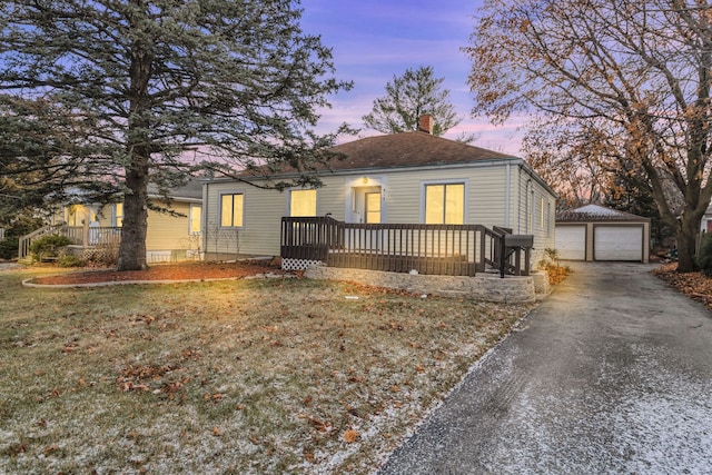 bungalow featuring a garage, an outdoor structure, and a yard