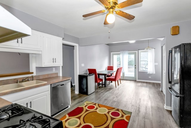 kitchen featuring ceiling fan, sink, black appliances, decorative light fixtures, and white cabinets