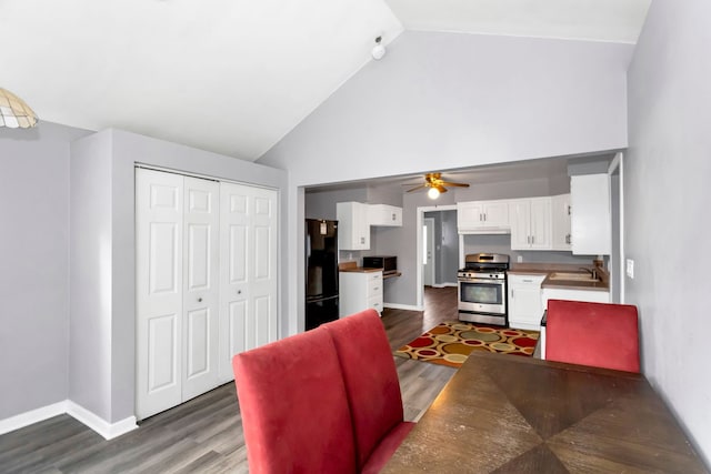 dining space featuring ceiling fan, dark hardwood / wood-style flooring, lofted ceiling, and sink