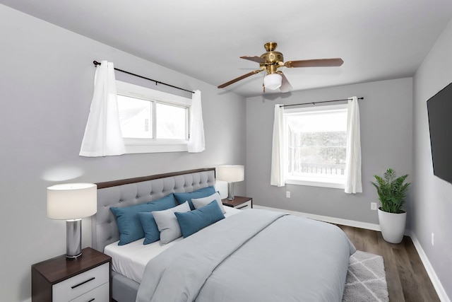 bedroom with ceiling fan, dark hardwood / wood-style flooring, and multiple windows