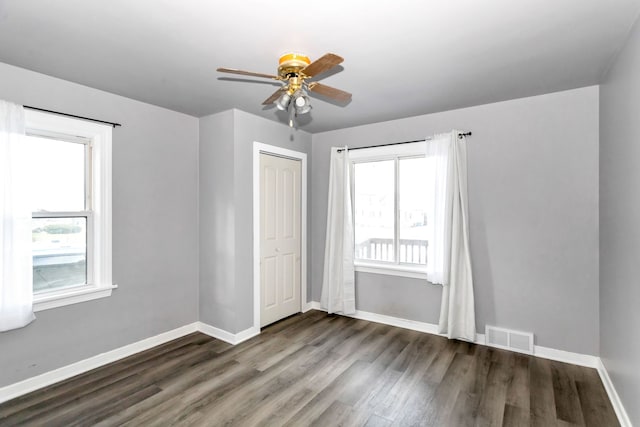 unfurnished bedroom with ceiling fan, a closet, and dark wood-type flooring