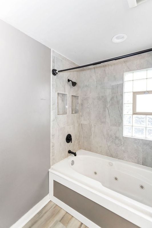 bathroom with hardwood / wood-style floors and tiled shower / bath