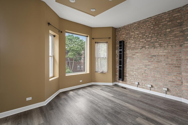 unfurnished room featuring brick wall and wood-type flooring