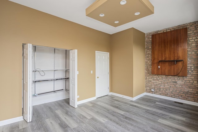 unfurnished bedroom with wood-type flooring and brick wall