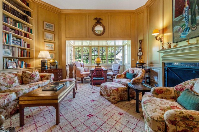 sitting room with a high ceiling, built in features, and a high end fireplace