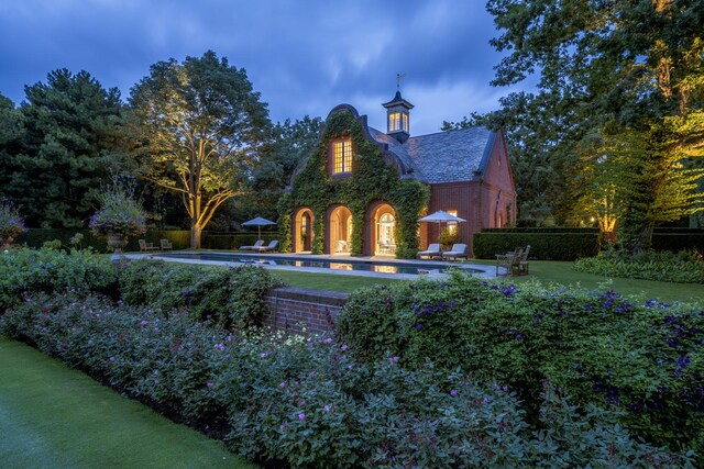 pool at dusk featuring a lawn