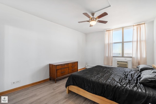 bedroom with a wall mounted air conditioner, ceiling fan, light hardwood / wood-style flooring, and a baseboard radiator