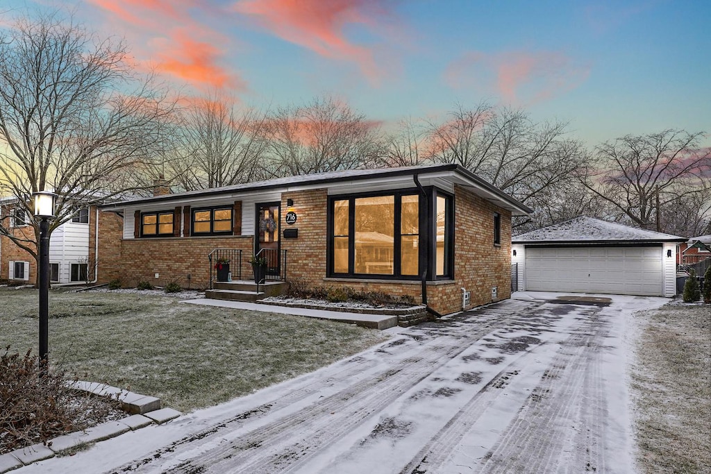 view of front of house with a garage, a yard, and an outbuilding