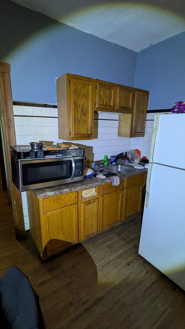 kitchen featuring sink, dark hardwood / wood-style flooring, white fridge, and backsplash