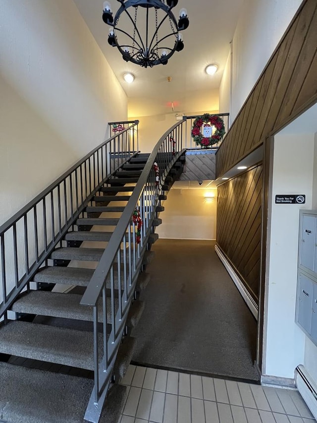 stairs featuring a baseboard radiator, tile patterned floors, and a notable chandelier