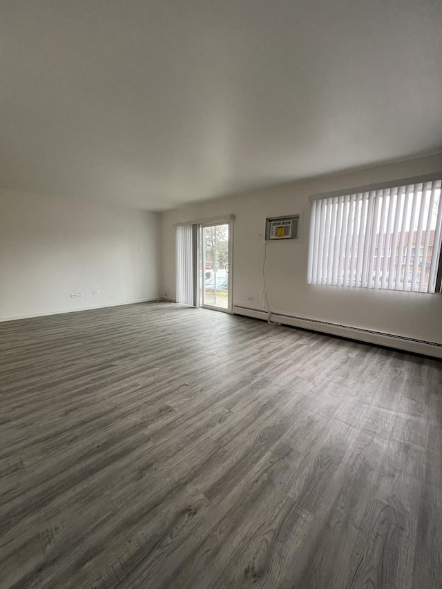 spare room with a wall unit AC, dark hardwood / wood-style floors, and a baseboard heating unit