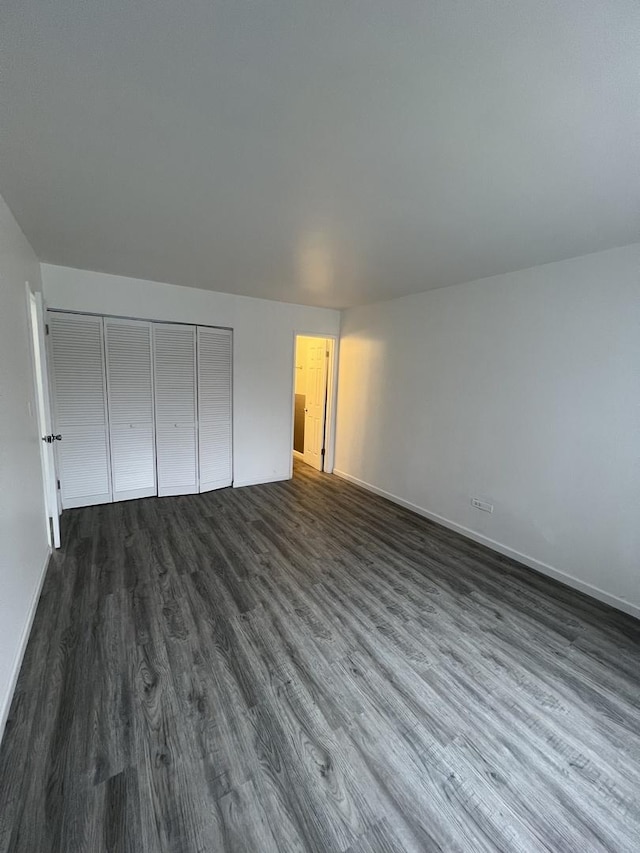 unfurnished bedroom with dark hardwood / wood-style floors and a closet