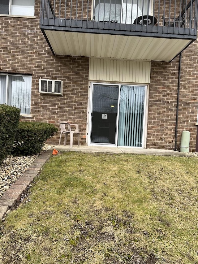 view of exterior entry with a yard and a balcony