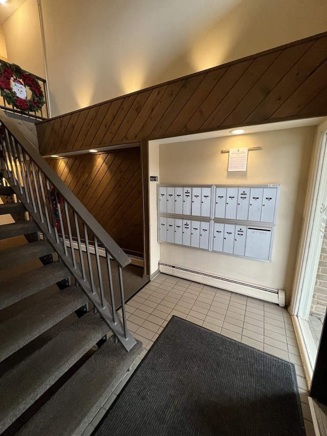 interior space featuring wood walls, a baseboard radiator, and a mail area