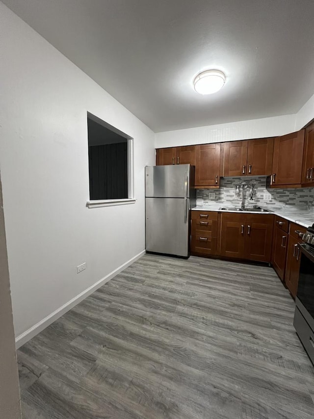 kitchen featuring tasteful backsplash, sink, stainless steel appliances, and wood-type flooring