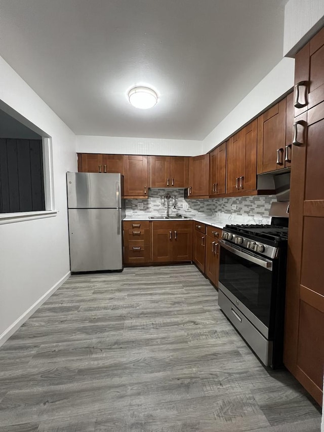 kitchen with light wood-type flooring, sink, appliances with stainless steel finishes, and tasteful backsplash