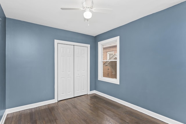 unfurnished bedroom with dark hardwood / wood-style flooring, a closet, and ceiling fan