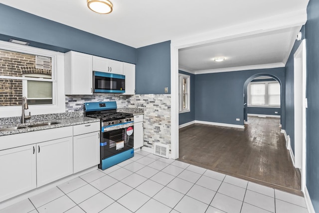 kitchen featuring white cabinets, stainless steel appliances, light stone counters, sink, and light tile patterned flooring