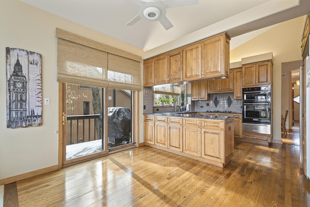 kitchen featuring ceiling fan, backsplash, black double oven, wood-type flooring, and vaulted ceiling