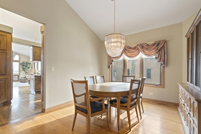 dining room featuring a notable chandelier, light hardwood / wood-style floors, and lofted ceiling