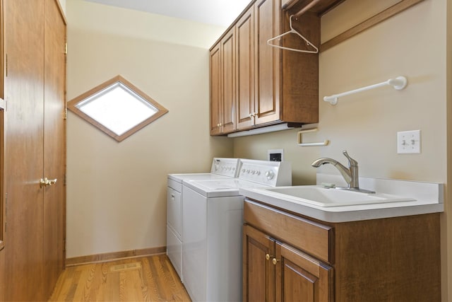 washroom featuring washer and dryer, sink, cabinets, and light hardwood / wood-style floors