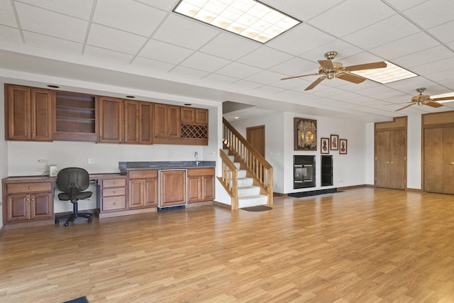 kitchen featuring a tiled fireplace, ceiling fan, and light hardwood / wood-style floors