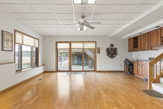 unfurnished living room featuring light wood-type flooring, a drop ceiling, and ceiling fan