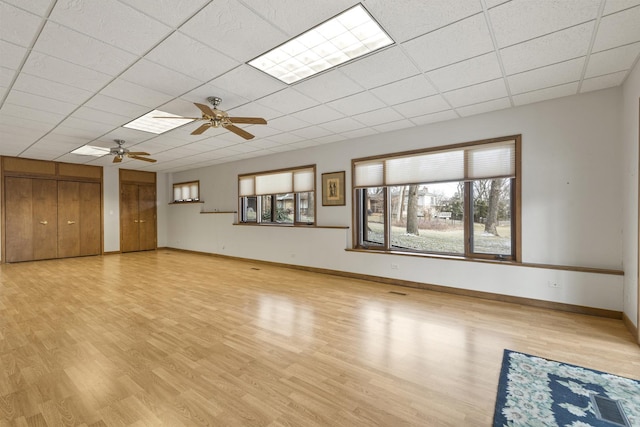 unfurnished living room with ceiling fan, a drop ceiling, and light hardwood / wood-style flooring