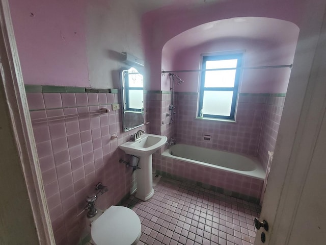 full bathroom with sink, tile walls, a wealth of natural light, and tile patterned flooring