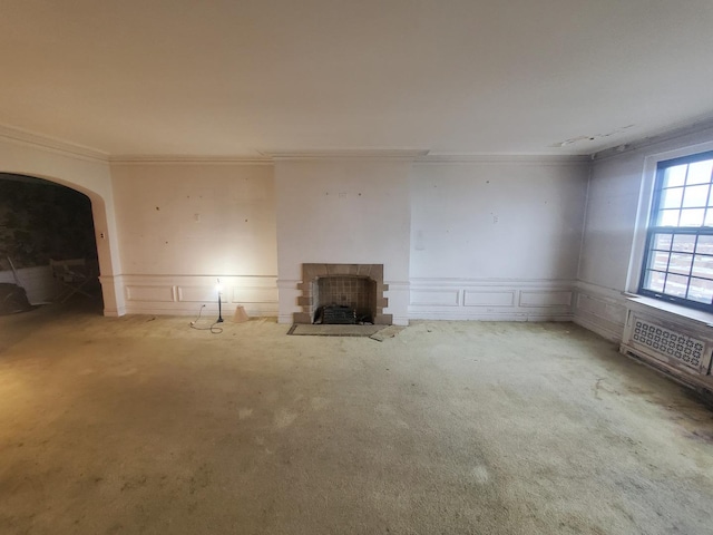 unfurnished living room featuring ornamental molding, light carpet, and a fireplace