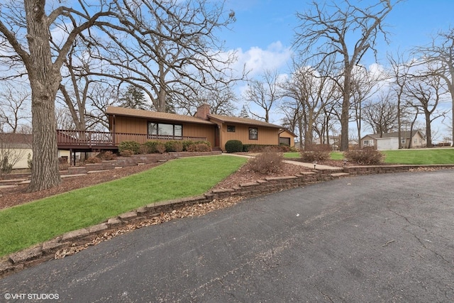 view of front facade with a wooden deck and a front yard