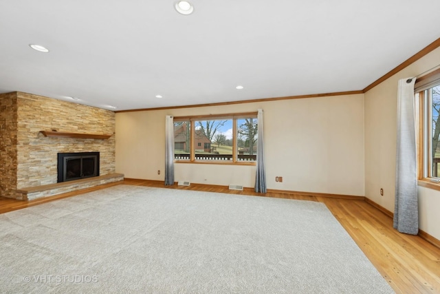 unfurnished living room featuring a stone fireplace, crown molding, and light wood-type flooring