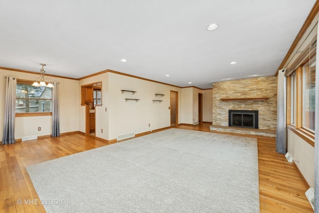 unfurnished living room with crown molding, a fireplace, wood-type flooring, and a notable chandelier