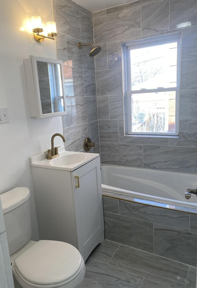 full bathroom featuring vanity, tiled shower / bath combo, and toilet