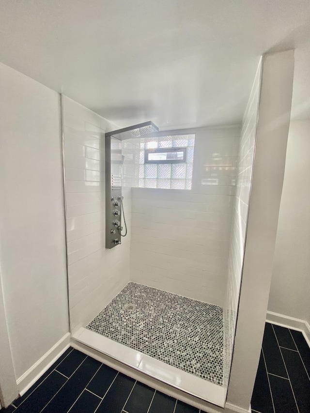 bathroom with tiled shower and tile patterned flooring