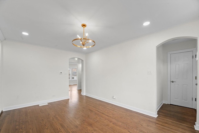 empty room with dark wood-type flooring, crown molding, and a notable chandelier