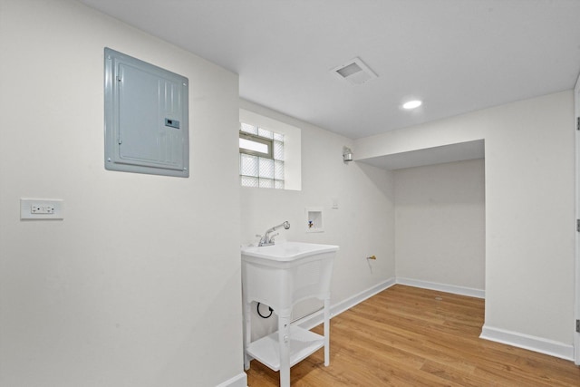 clothes washing area with hookup for a washing machine, electric panel, and hardwood / wood-style flooring