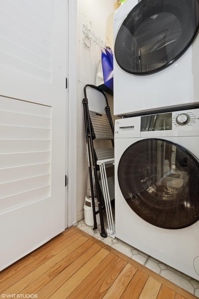 laundry area with wood-type flooring and stacked washer / dryer