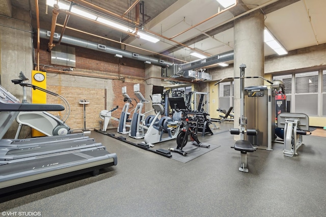 gym featuring a towering ceiling and brick wall