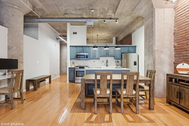 kitchen with blue cabinetry, sink, tasteful backsplash, light hardwood / wood-style floors, and appliances with stainless steel finishes