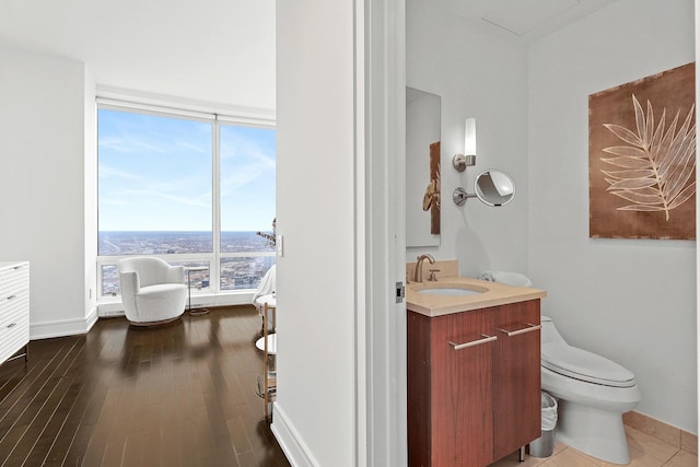 bathroom featuring hardwood / wood-style flooring, vanity, toilet, and a wall of windows