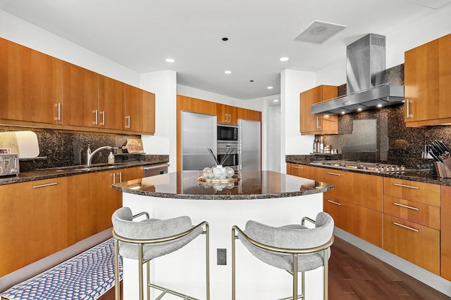 kitchen with a kitchen bar, dark hardwood / wood-style flooring, backsplash, wall chimney exhaust hood, and stainless steel appliances