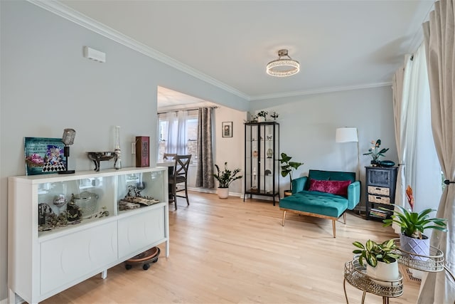 living area with light wood-type flooring and ornamental molding